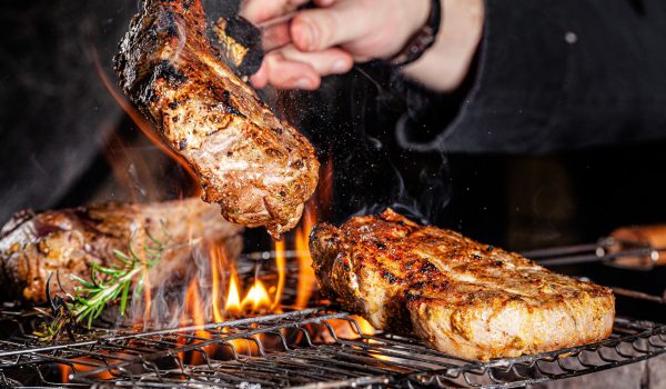 Chef cook fries meat, beef steak on an open fire in a restaurant. background image, copy space text